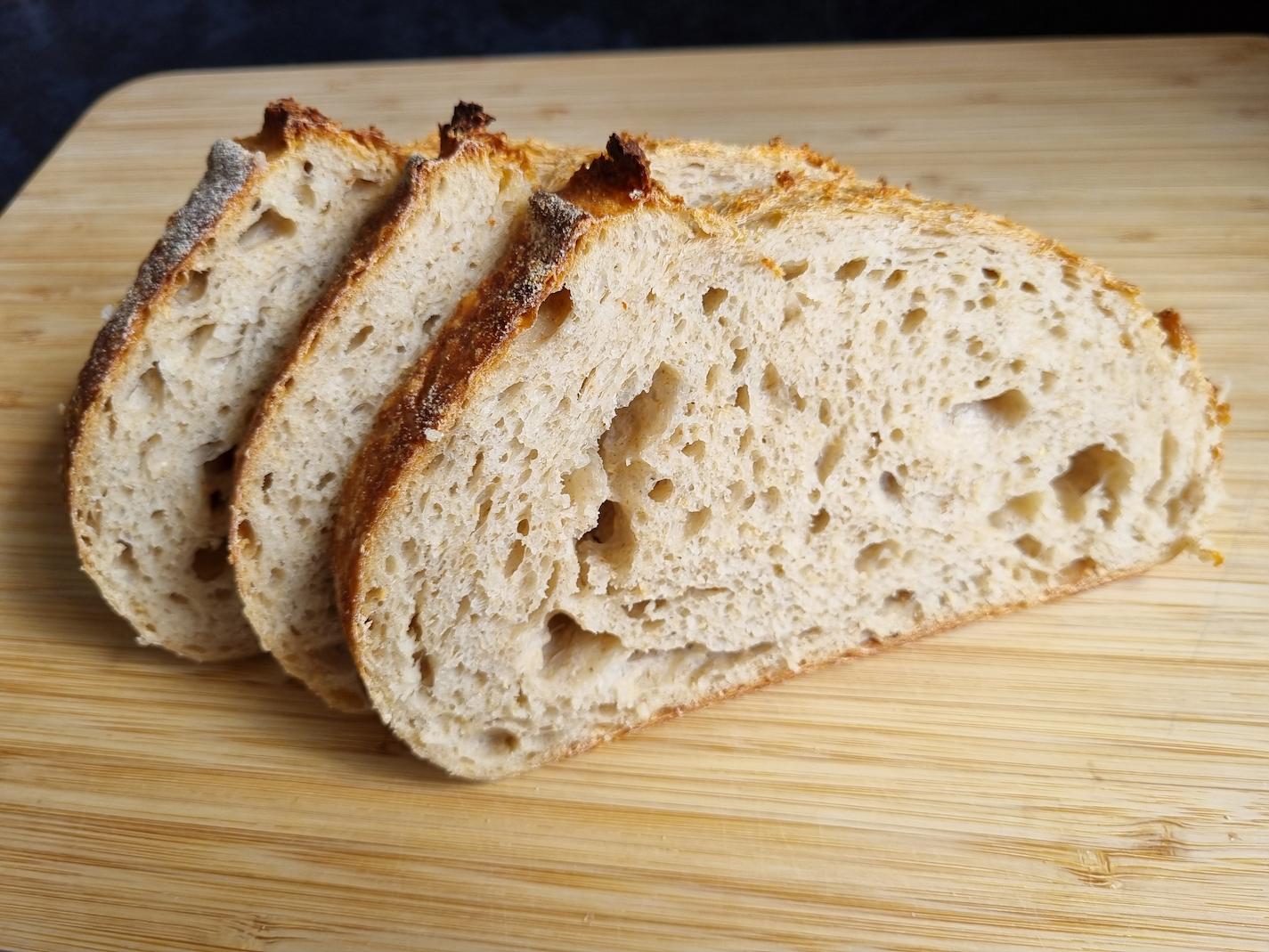 Slices of a sourdough loaf, Pain De Campagne, displayed on a wooden board.
