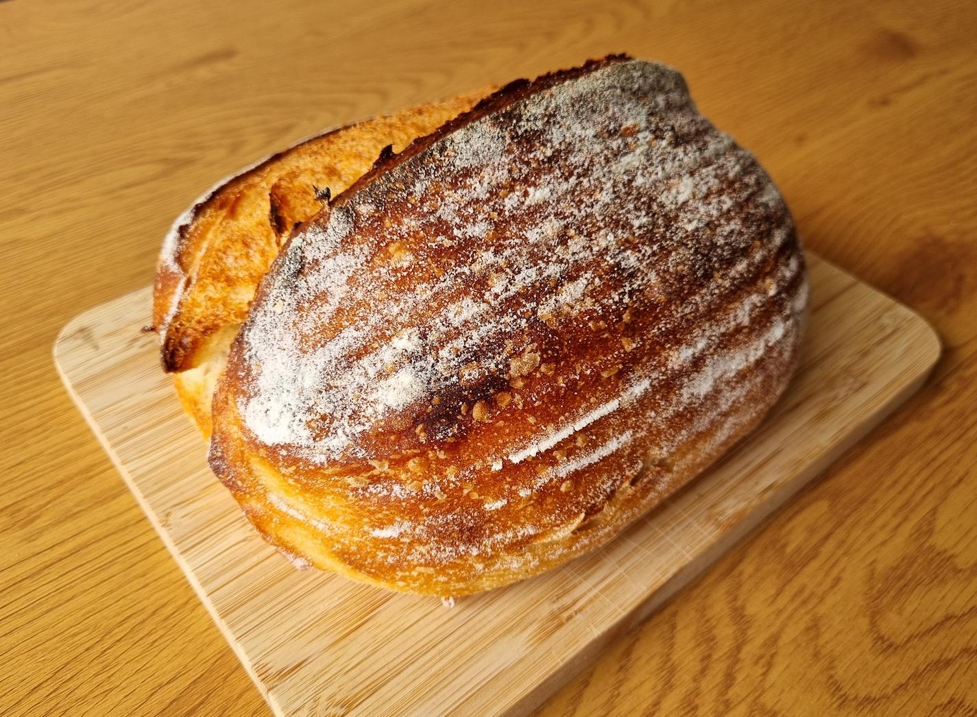 A freshly baked sourdough loaf on a wooden board.