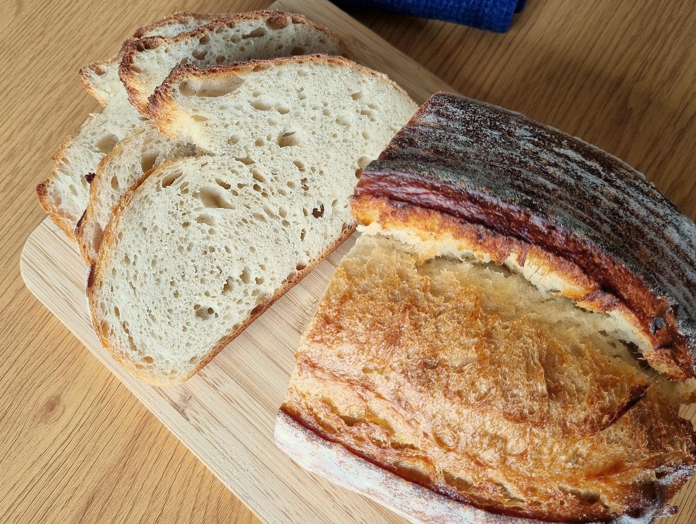 A freshly baked sourdough loaf, sliced on a wooden board.